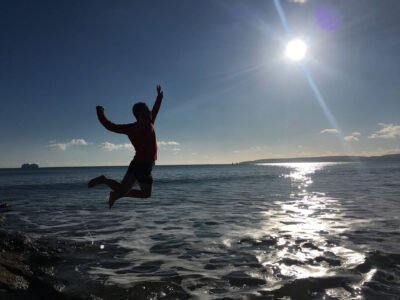 Manu saltando sobre el agua tratando de alcanzar su meta, el sol.